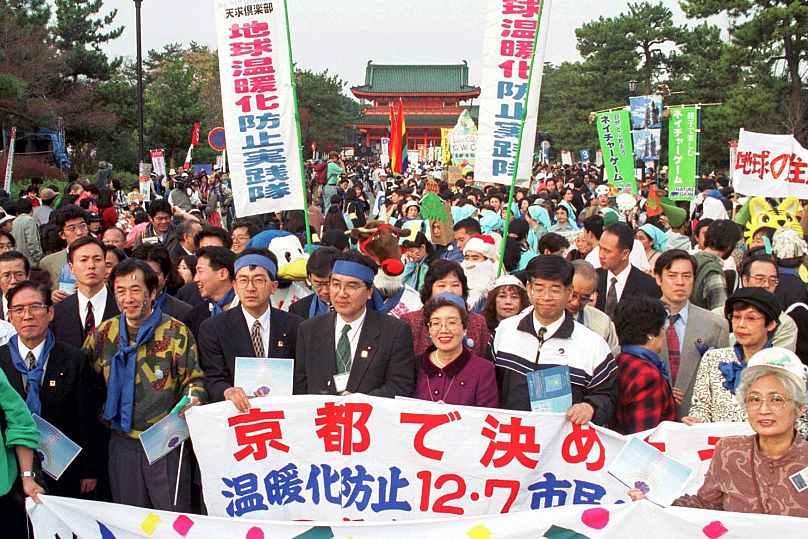 Des écologistes et des citoyens brandissent des banderoles appelant à la réduction des émissions de gaz à effet de serre devant le sanctuaire Heian à Kyoto, dans l'ouest du Japon, en 1997.