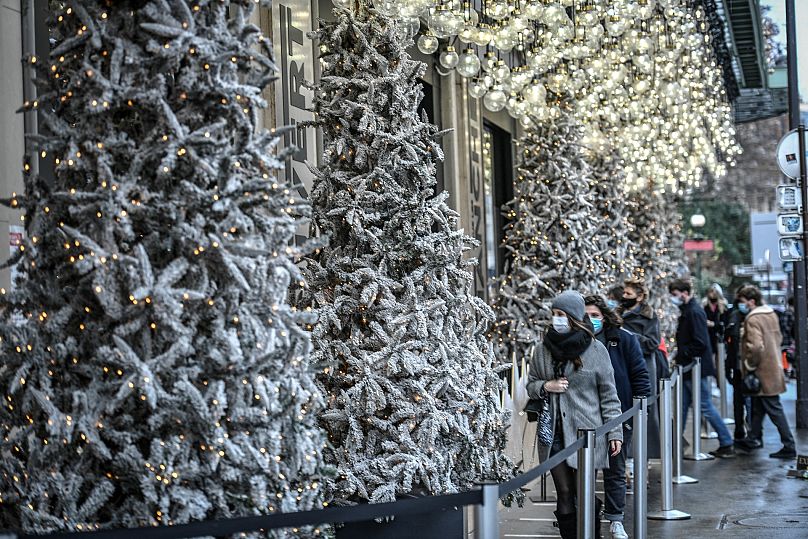 Des personnes portant des masques passent devant les vitrines décorées d'un grand magasin à Paris le 24 décembre 2020, la veille de Noël, au milieu de la pandémie de Covid-19, provoquée par le nov.