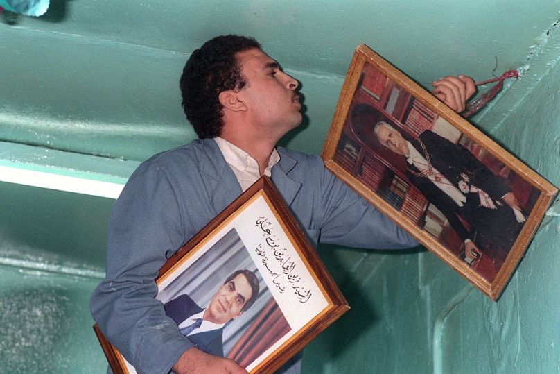 Un commerçant tunisien remplace le portrait de l'ancien président Habib Bourguiba par celui du nouveau président Zine el-Abidine Ben Ali à Tunis, novembre 1987.