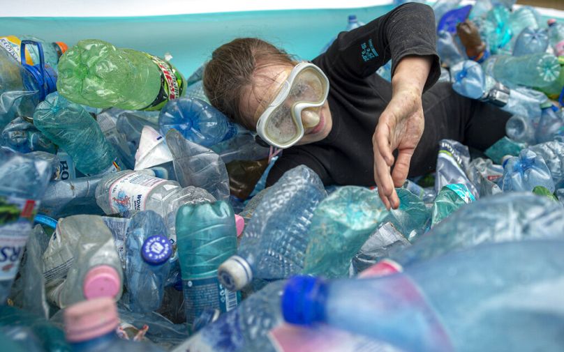 Un activiste imite qu'il nage dans une piscine gonflable remplie de bouteilles en plastique PET lors d'une manifestation devant le ministère de l'Environnement à Bucarest, juin 2021.