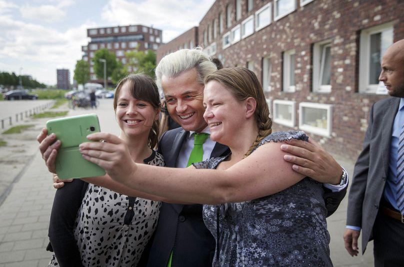 Geert Wilders, leader du Parti néerlandais pour la liberté, pose pour un selfie avec ses partisans tandis que son garde du corps surveille après avoir voté à La Haye, mai 2014.