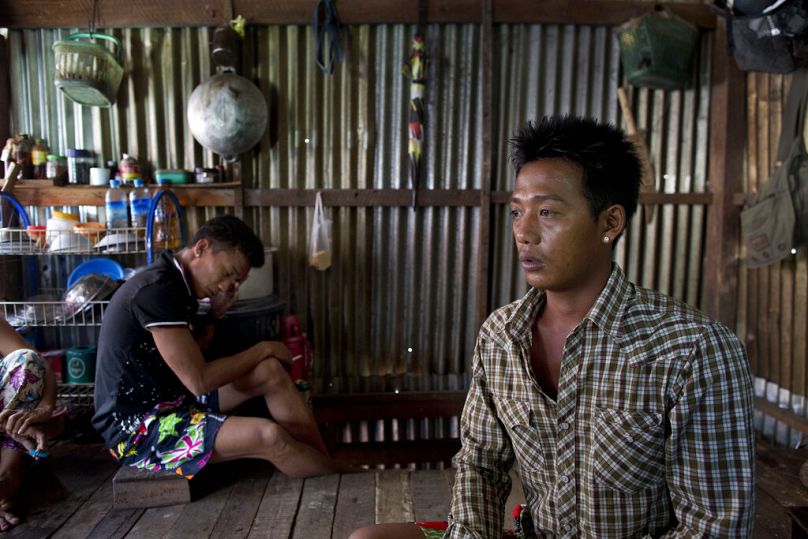 L'ancien pêcheur esclave birman Lin Lin, à droite, parle de ses amis disparus en mer tandis que Kaung Htet Wai, à gauche, fume une cigarette dans une cabane à la périphérie de Yangon, juillet 2015.