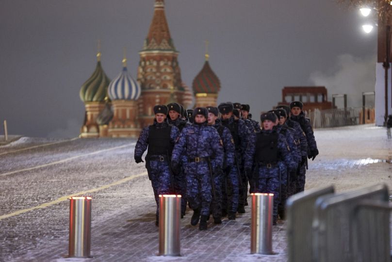 Des policiers et des militaires de la Rosguardia (Garde nationale) marchent sur la Place Rouge avec la cathédrale Saint-Basile en arrière-plan à Moscou, en Russie, le dimanche 31 décembre 2023.