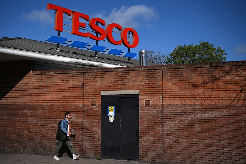 Un piéton passe devant une succursale de la chaîne de supermarchés britannique Tesco, dans l'est de Londres, le 13 avril 2023. Le plus grand détaillant britannique, le groupe de supermarchés Tesco, a rapporté jeudi 13 avril.