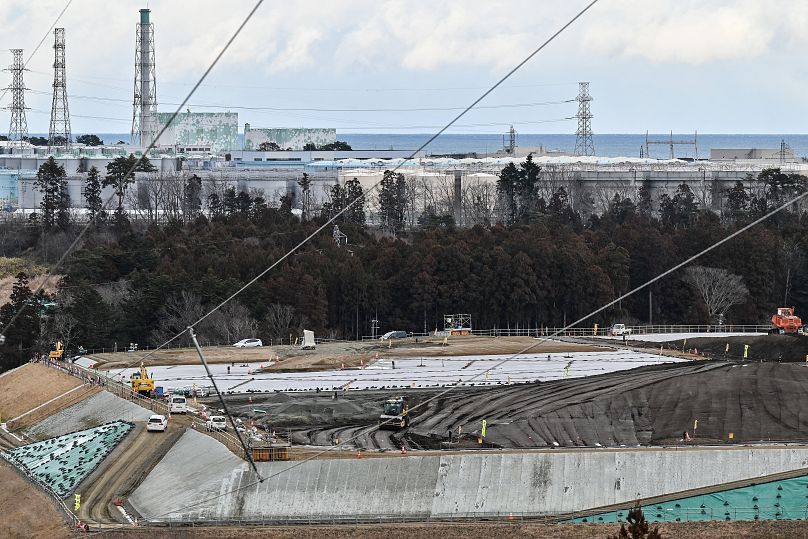 Cette photo prise le 14 février 2023 montre un site (en bas) où le sol contaminé par l'accident nucléaire de 2011 à la centrale nucléaire de Fukushima Daiichi (en haut) est placé.