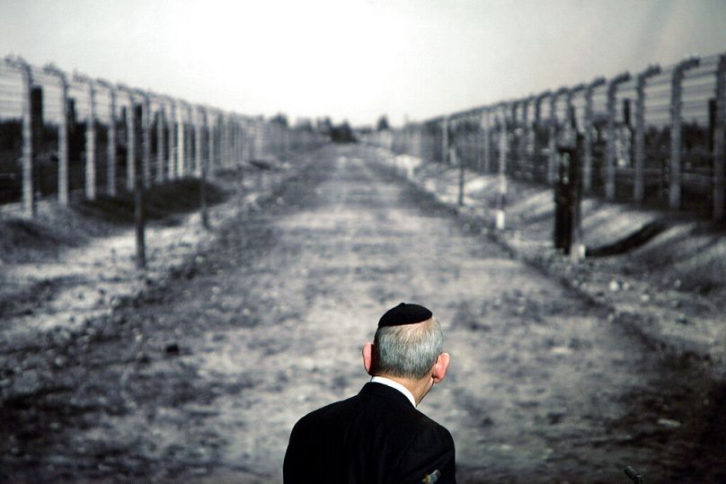 Le rabbin Israel Singer, président du Congrès juif mondial, regarde une photo montrant un couloir du camp de concentration d'Auschwitz.