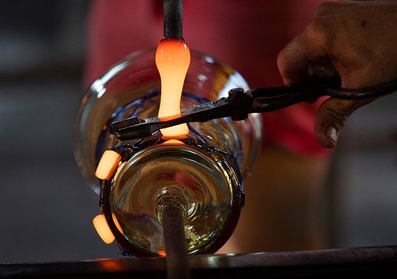 Un maître artisan coupe du verre brillant alors qu'il travaille une pièce à la verrerie Vidrios Guardiola à Algaida, sur l'île de Majorque, Espagne, le 27 août 2021.