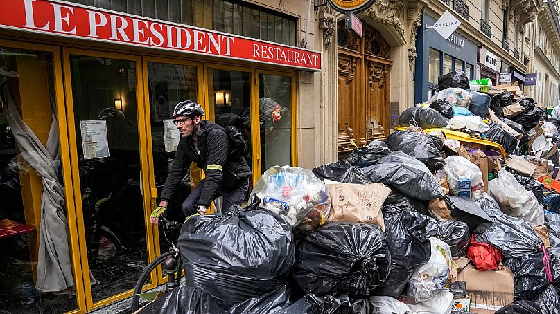 Un cycliste passe devant un tas d'ordures non ramassées à côté d'un café à Paris, le 21 mars 2023.