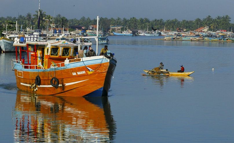 Des pêcheurs sri-lankais se tiennent sur un bateau de pêche alors qu'il quitte un port de pêche à Negombo, dans la banlieue de Colombo, en octobre 2014.