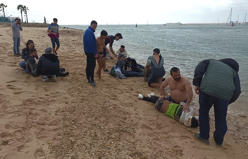 Des migrants sont secourus par des habitants au bord d'une plage, près de la ville de Cadix, dans le sud-ouest de l'Espagne.