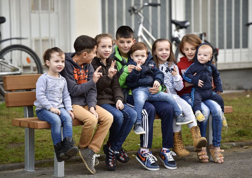 Des enfants migrants sont assis sur un banc et brandissent le signe de la victoire en attendant la visite du président allemand Joachim Gauck à Bergisch Gladbach, dans l'ouest de l'Allemagne.