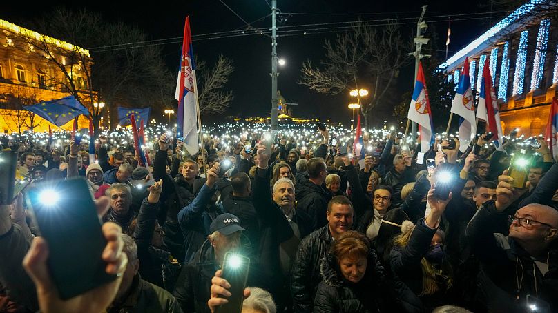 Des partisans de l'opposition serbe brandissent des lumières lors d'une manifestation devant le bâtiment de la commission électorale à Belgrade