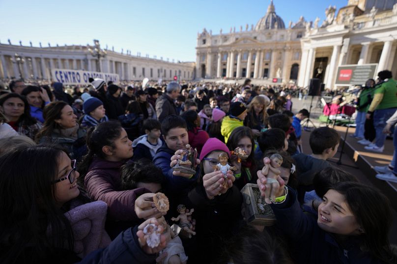 Des enfants brandissent des statues de l'enfant Jésus en attendant la prière de l'Angélus de midi du pape François