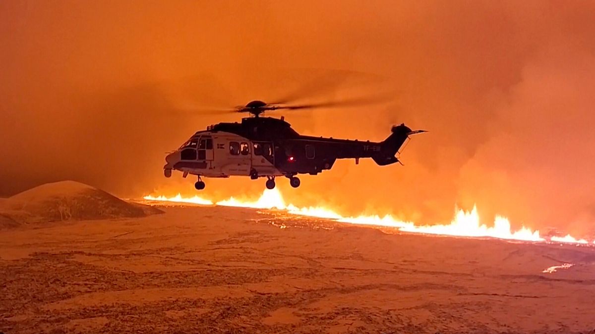 An Icelandic Coast Guard helicopter flies near magma running on a hill near Grindavik on Iceland