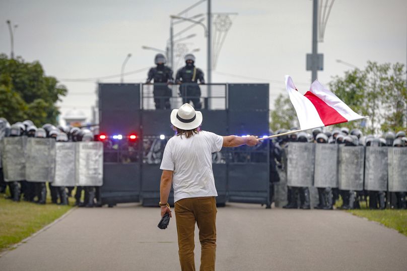 L'artiste Ales Pouchkine, décédé en juillet alors qu'il était emprisonné en Biélorussie pour violation des droits de l'homme, brandit un drapeau rouge et blanc symbolisant l'opposition à Loukachanko en 2020.