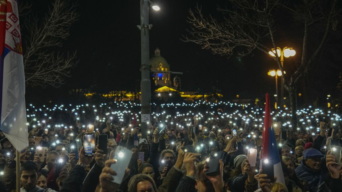 Serbian opposition supporters hold lights during protest outside the electoral commission building in Belgrade, Serbia, Sunday, Dec. 24, 2023.