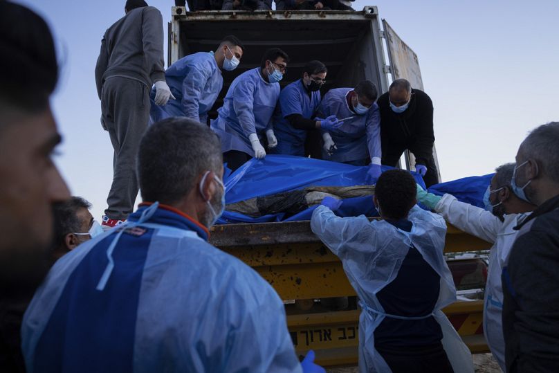 Des médecins déchargent les corps des Palestiniens tués dans les combats avec Israël et remis par l'armée israélienne lors de funérailles collectives à Rafah, dans la bande de Gaza, le mardi 26 décembre.