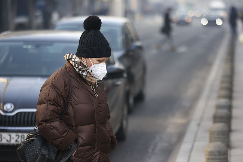 Une femme porte un masque facial enveloppé par une brume de pollution alors que le smog recouvre Sarajevo, en Bosnie, le mercredi 20 décembre 2023.