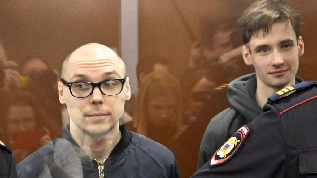 Russian poets Artyom Kamardin (L) and Yegor Shtovba (R) stand inside the defendants