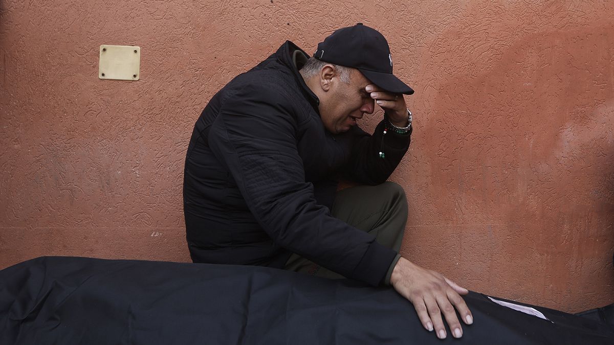 A Palestinian man mourns a relative killed in the Israeli bombardment of the Gaza Strip outside a morgue in Khan Younis, 23 December 2023