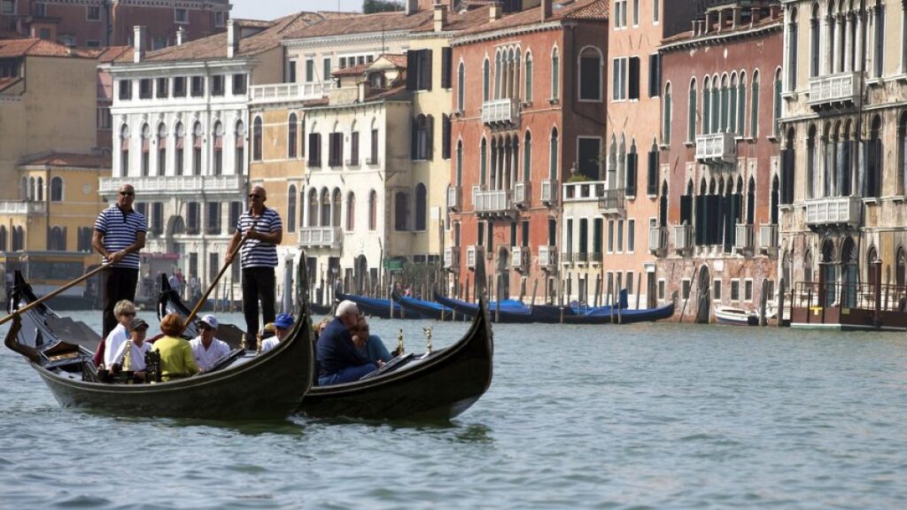 Tourists tour the Grand Canal on traditional Gondola Venetian boats, in Venice, Italy