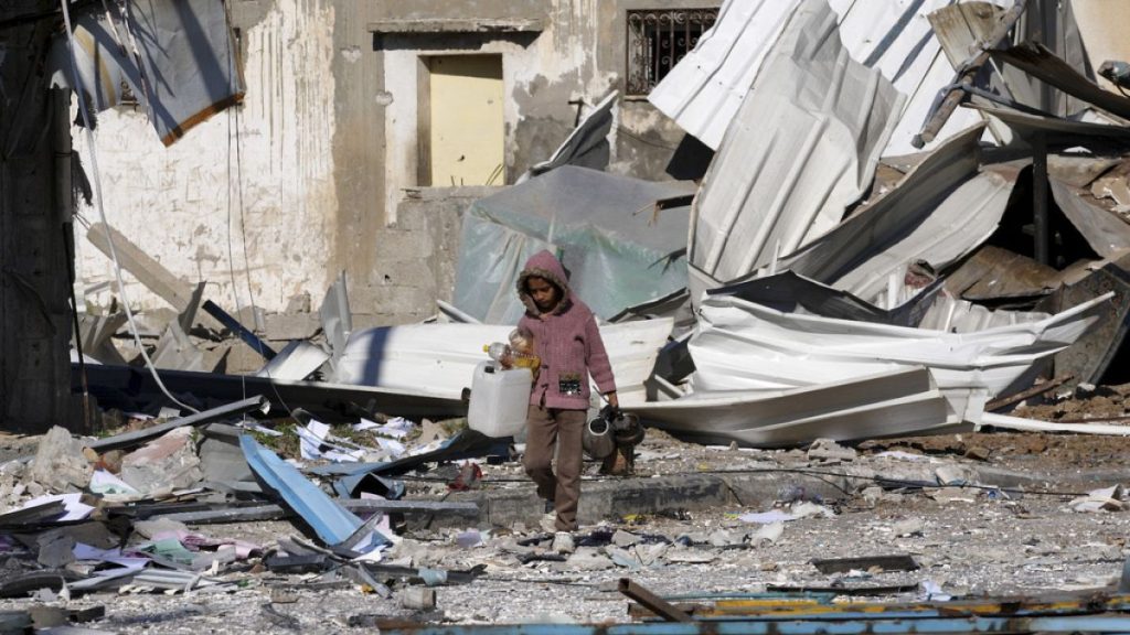 A Palestinian child walks past factories destroyed in the Israeli bombardment of the Gaza Strip in Deir al Balah on Saturday, Jan. 13, 2024