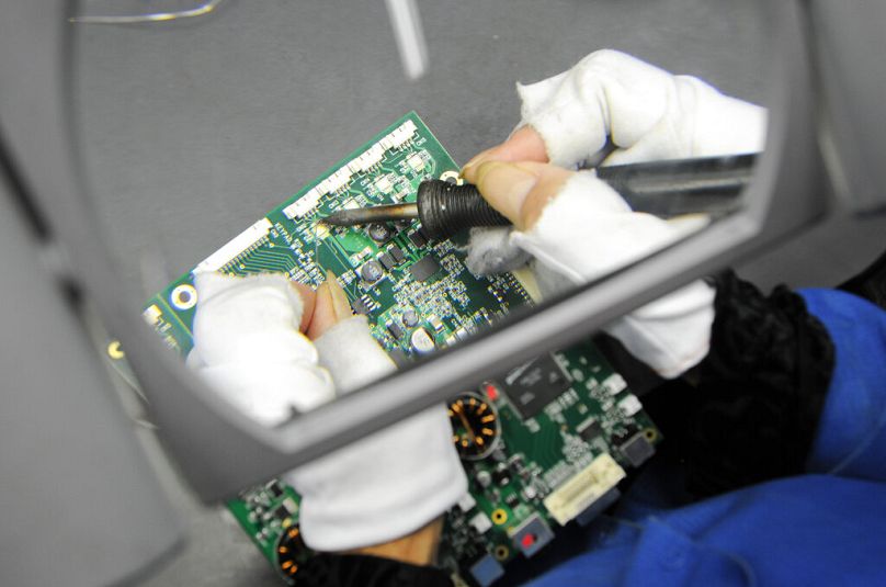 Une personne effectue un travail détaillé de soudure sur un circuit imprimé à Hillsboro, Oregon, septembre 2010