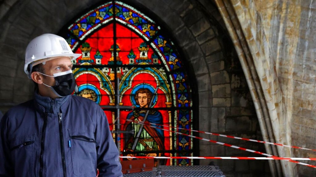 French President Emmanuel Macron stands by a stained glass at the reconstruction site of the Notre-Dame de Paris cathedral on April 15, 2021.