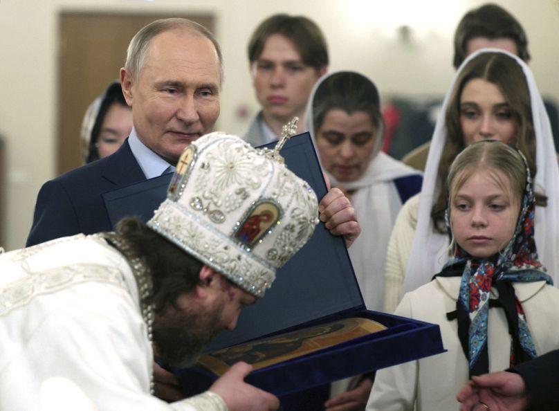 L'archevêque orthodoxe russe d'Odintsovo et de Krasnogorsk Foma (Nikolay Mosolov), au premier plan, embrasse une icône tandis que le président russe Vladimir Poutine, à gauche, se tient à proximité.