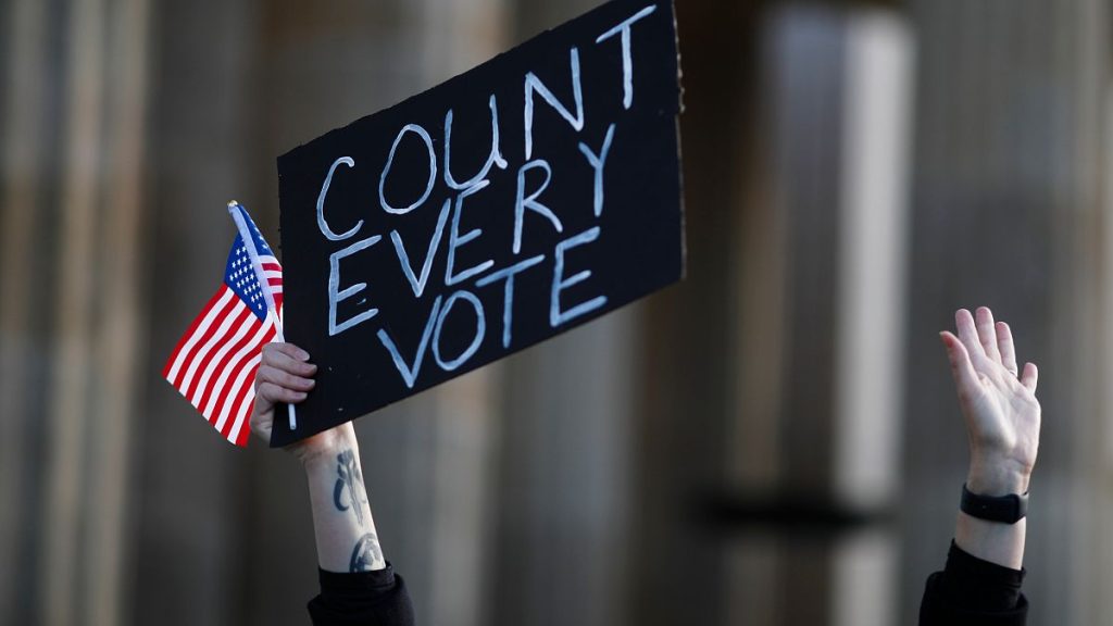 A woman shows a poster as she attends a Democrats Abroad rally in Berlin, 2020.