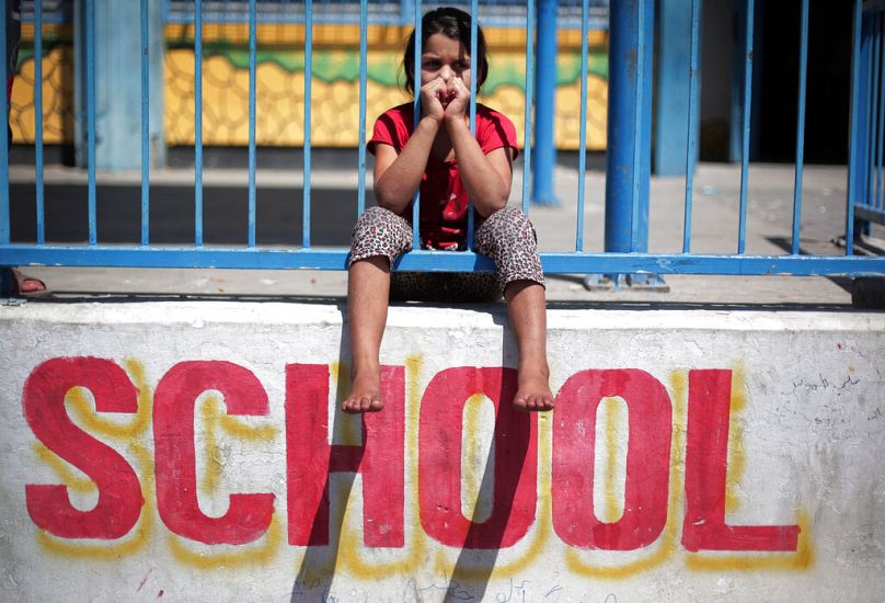 DOSSIER – Photo du 14 juillet 2014, une jeune fille palestinienne est assise sur le mur de l’école des Nations Unies de New Gaza.