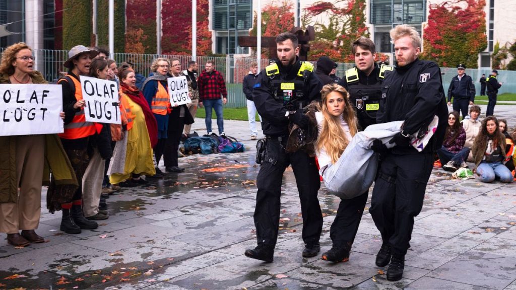 Police officers carry away an activist of the