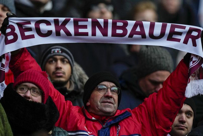 Un homme tient un foulard lors d'un service commémoratif pour la légende du Bayern et de l'Allemagne Franz Beckenbauer à l'Allianz Arena de Munich, en Allemagne, le vendredi 19 janvier 2024.