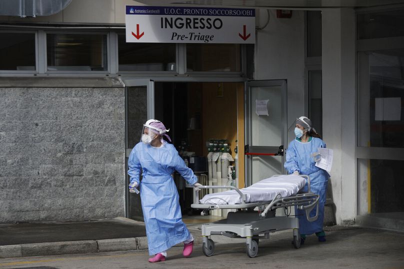 Des ambulanciers paramédicaux et des médecins se trouvent devant la zone de premiers secours de l'hôpital Cardarelli de Naples, en Italie, le vendredi 13 novembre 2020.