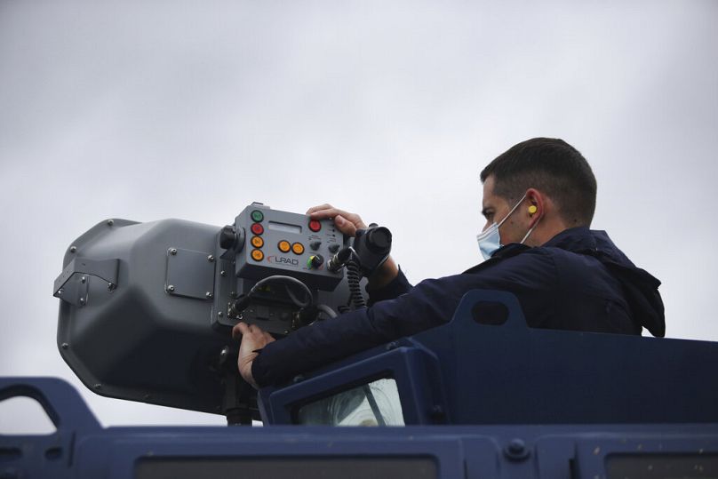 Un policier grec utilise un dispositif acoustique à longue portée, LRAD, lors d'une patrouille le long de la frontière gréco-turque, près de la ville de Feres, en mai 2021.