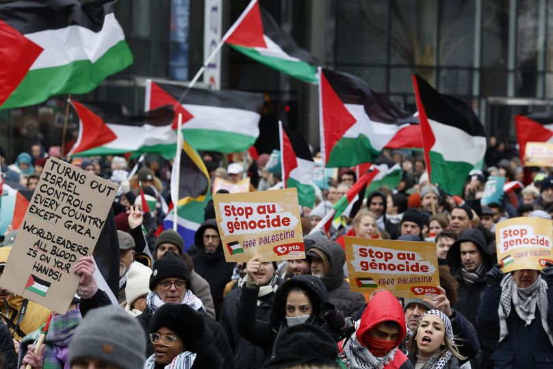 Des manifestants brandissent des pancartes et brandissent des drapeaux lors d’un rassemblement pro-palestinien à Bruxelles, le dimanche 21 janvier 2024.