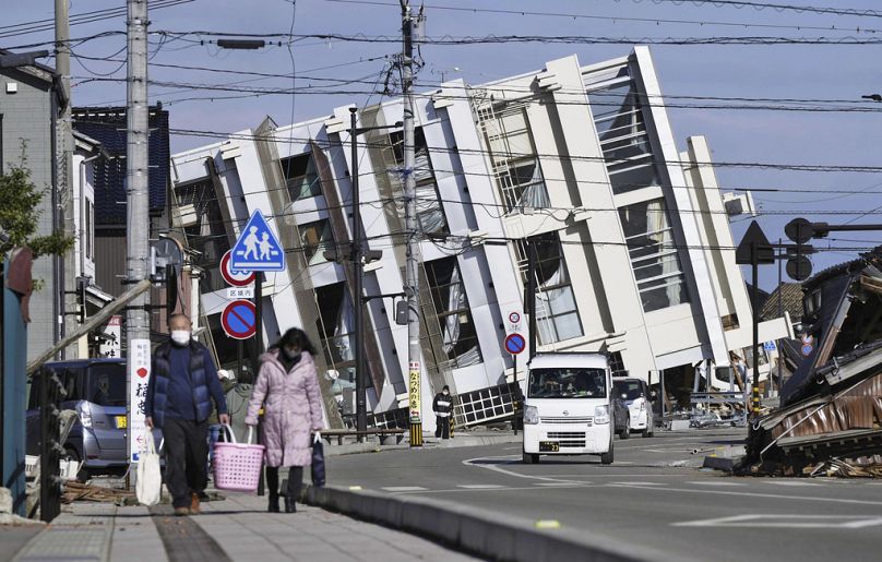 Des gens se dirigent vers un bâtiment effondré suite à un tremblement de terre à Wajima, préfecture d'Ishikawa, Japon