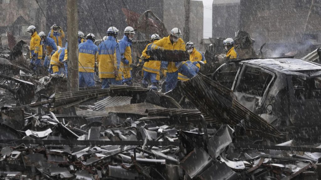 Police officers remove the debris from a fire at a market in Wajima, Ishikawa prefecture, Japan Saturday, Jan. 6, 2024.