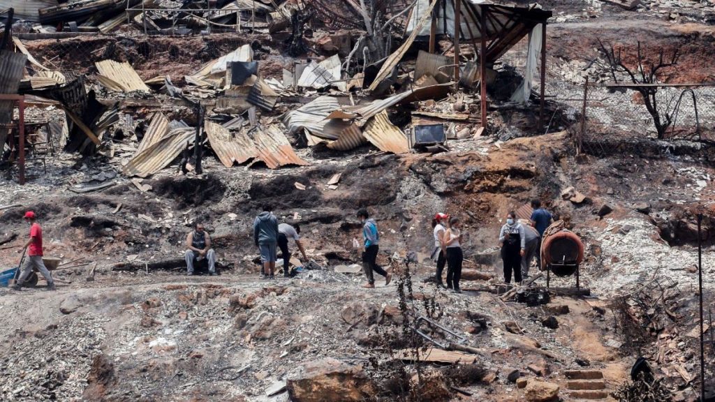 Locals clean the rubble of burnt-out houses after forest fires reached their neighborhood in Vina del Mar, Chile, Sunday, Feb. 4, 2024.