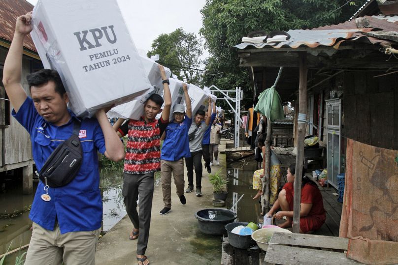 Des agents électoraux transportent des urnes lors de la distribution d'accessoires électoraux dans des villages reculés, à Pemulutan, dans le sud de Sumatra, en février 2024.