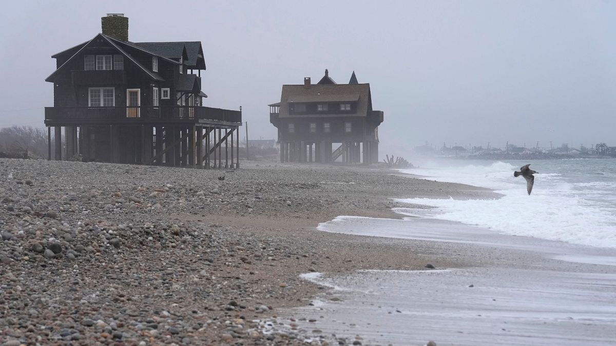 Seagulls fly near houses resting on pylons elevated above the beach, 25 January 2024, in South Kingstown, RI.