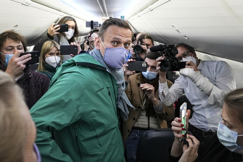 DOSSIER - Alexei Navalny est entouré de journalistes dans un avion avant un vol à destination de Moscou à l'aéroport de Berlin Brandenburg, le 17 janvier 2021.