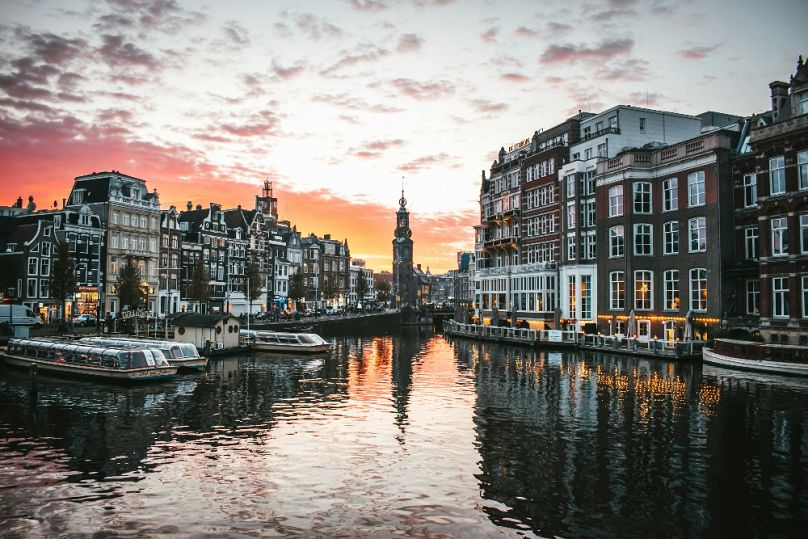 Coucher de soleil sur la Muntplein à Amsterdam, reflété dans les magnifiques canaux de la ville