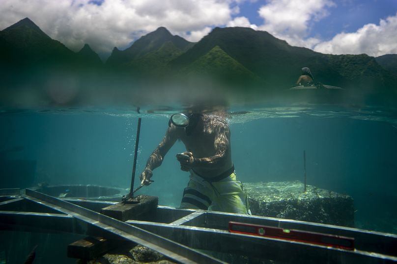 Un ouvrier inspecte les fondations permanentes en construction sur le récif de corail pour une tour de jugement qui sera utilisée pendant les Jeux Olympiques.