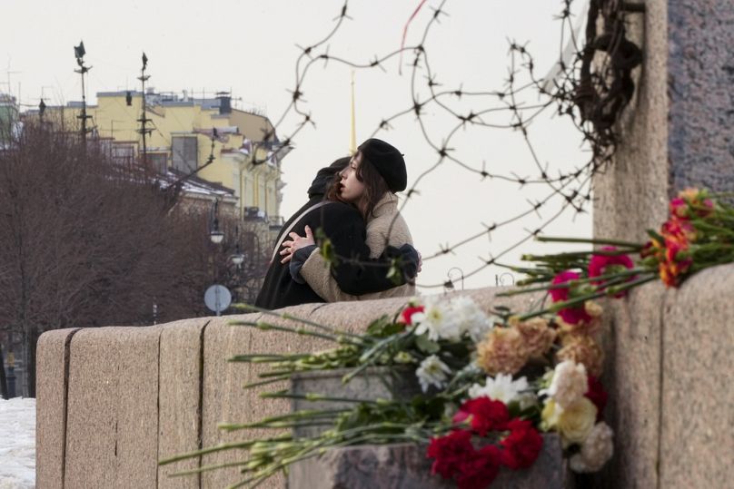 Des femmes s'embrassent après avoir déposé des fleurs au Mémorial des victimes de la répression politique pour rendre hommage à Alexei Navalny à Saint-Pétersbourg.