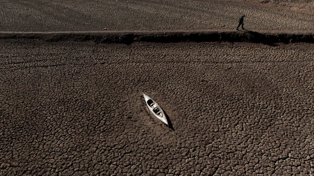 A man walks past an abandoned canoe at the Sau reservoir.