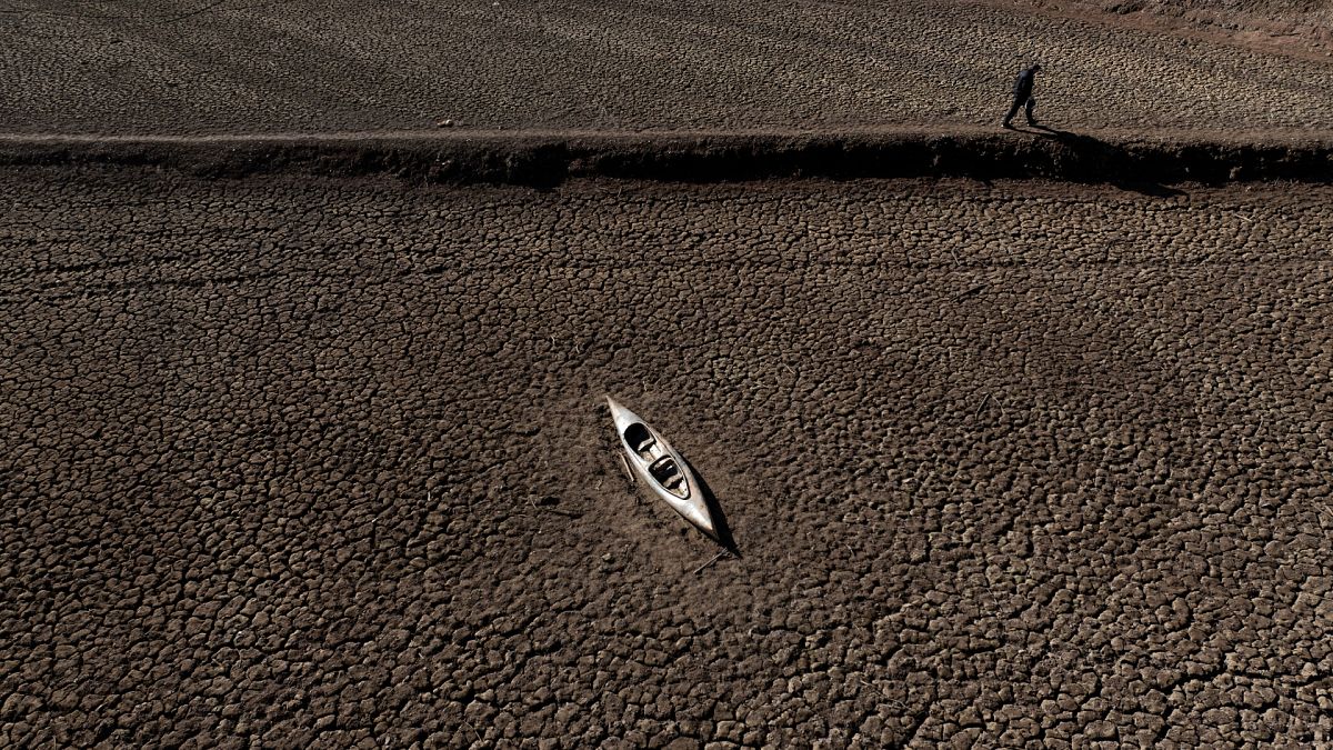 A man walks past an abandoned canoe at the Sau reservoir.