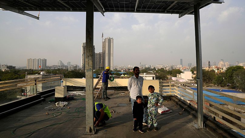 Des enfants et leur père regardent les panneaux solaires nouvellement installés sur le toit de leur maison à Gurugram, dans la banlieue de New Delhi.