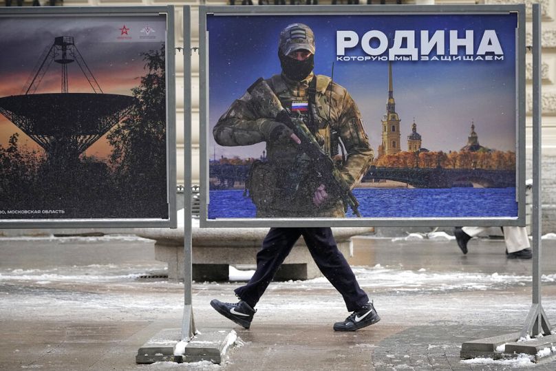 Un homme passe devant un stand avec l'image d'un militaire russe lors d'une exposition de photos militaires à Saint-Pétersbourg, en février 2023.