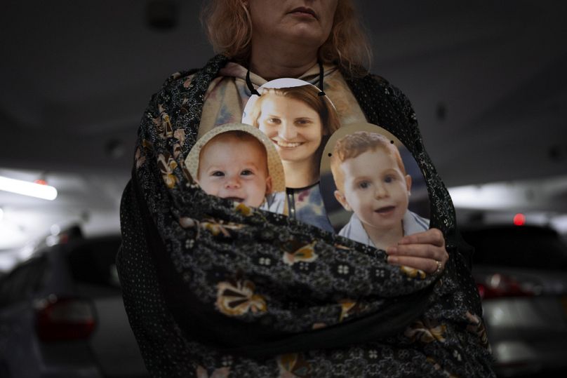 Une femme tient un masque représentant les visages de Shiri Bibas et de ses fils Kfir et Ariel, Israéliens retenus en otage par le Hamas, lors d'une manifestation à Tel Aviv, février 2024.